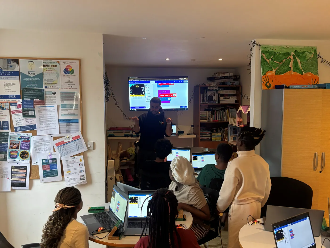 A mentor teaching Micro:bit coding to a small group at a community centre